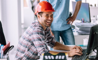 Servicetechniker mit Helm am Computer