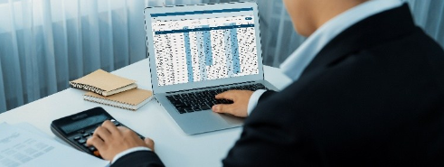 Person bei der Arbeit am Laptop mit Taschenrechner